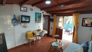 Zona d'estar acollidora amb televisió, taula de dinar, cadires i una petita taula de cafè.
