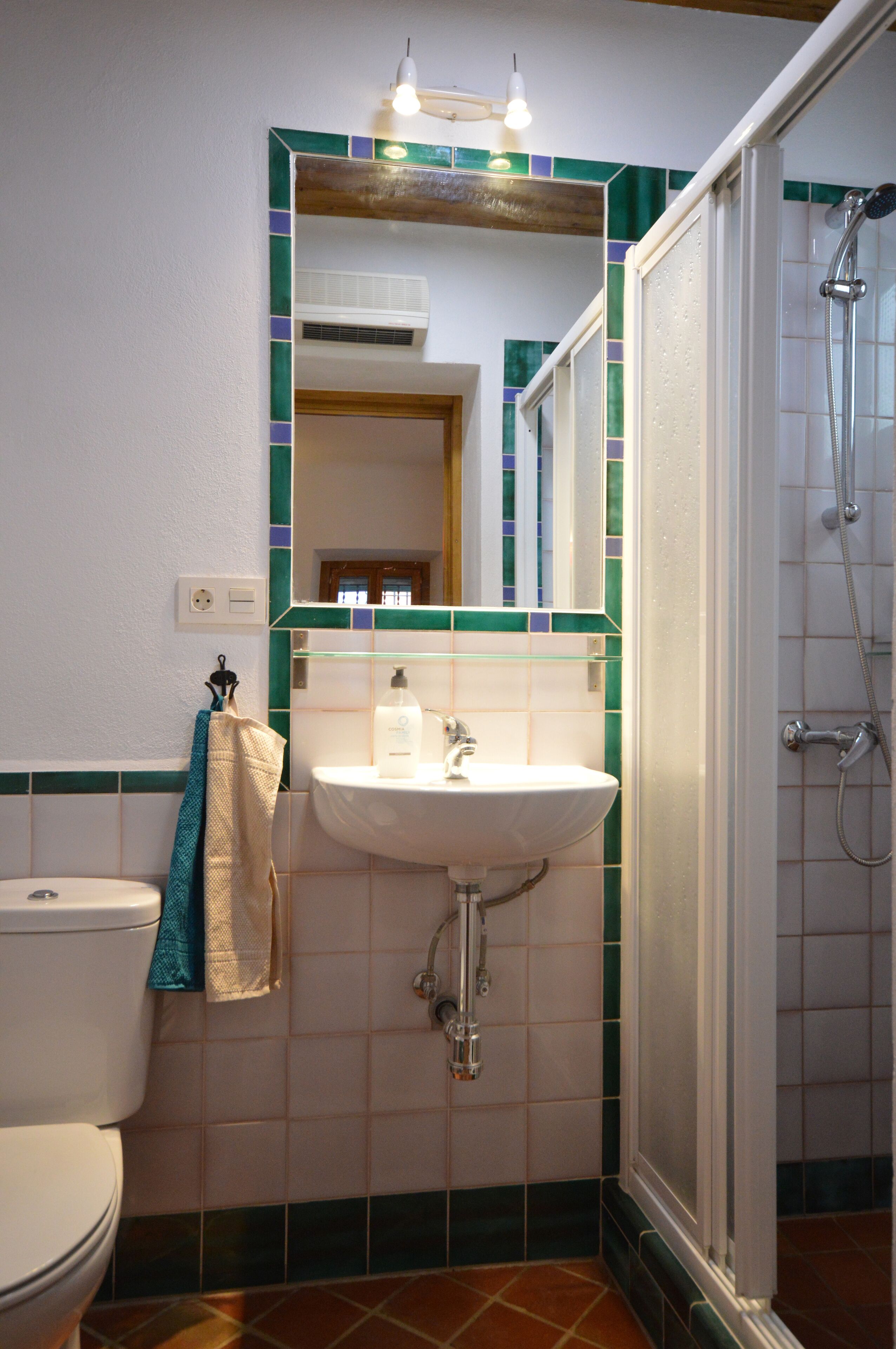 Un baño con lavamanos blanco, espejo y ducha.