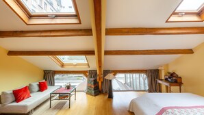 Une pièce avec un lit en mezzanine, un canapé, un bureau et une lucarne.