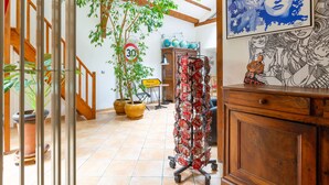 Une pièce avec un escalier, des plantes en pot, une collection de globes terrestres et un chariot contenant des objets rouges.