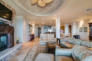 A spacious living room with a fireplace, leather sofas, and a dining area with chairs.