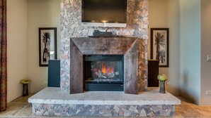 Una chimenea de piedra con un televisor de pantalla plana montado encima, rodeada de obras de arte enmarcadas.