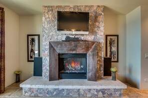 A stone fireplace with a flat-screen TV mounted above it, surrounded by framed artwork.