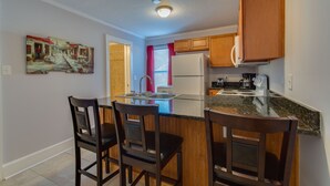 A modern kitchen with a central island, wooden cabinets, and a painting on the wall. - F1, Downtown St. Augustine, POOL, beaches, free onsite parking! (Saint Augustine)