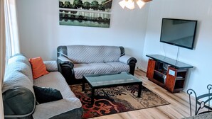 Una sala de estar con sofá, mesa de centro, televisor y ventilador de techo.