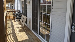 Una terraza techada al aire libre con barandilla de madera, una mesa y sillas.