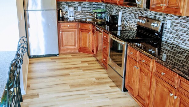 Una cocina con gabinetes de madera, electrodomésticos de acero inoxidable y salpicadero de azulejos.