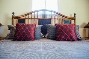 A bed with a wooden headboard, multiple pillows, and a patterned bedspread.