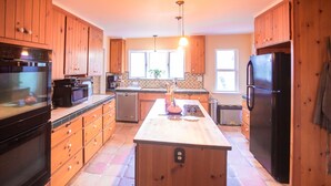 Una cocina con armarios de madera, una isla central, un refrigerador y una estufa.