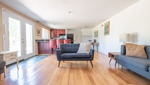 Un salón amplio con un sofá gris oscuro, un sofá azul y suelo de madera.