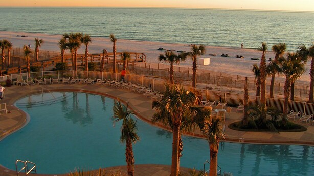 A pool area with a view of the beach and ocean.