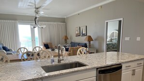 A modern kitchen with white cabinets, a stainless steel dishwasher, and a granite countertop.