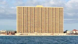 Un hotel grande y de varios pisos con una fachada uniforme, situado cerca de una playa y vistas al mar.