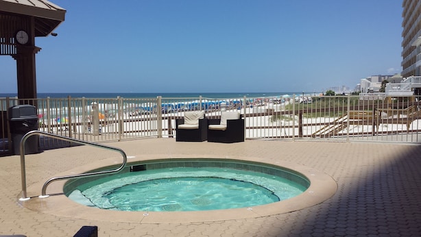 Zona de piscina con vista a la playa, un reloj y un cubo de basura.