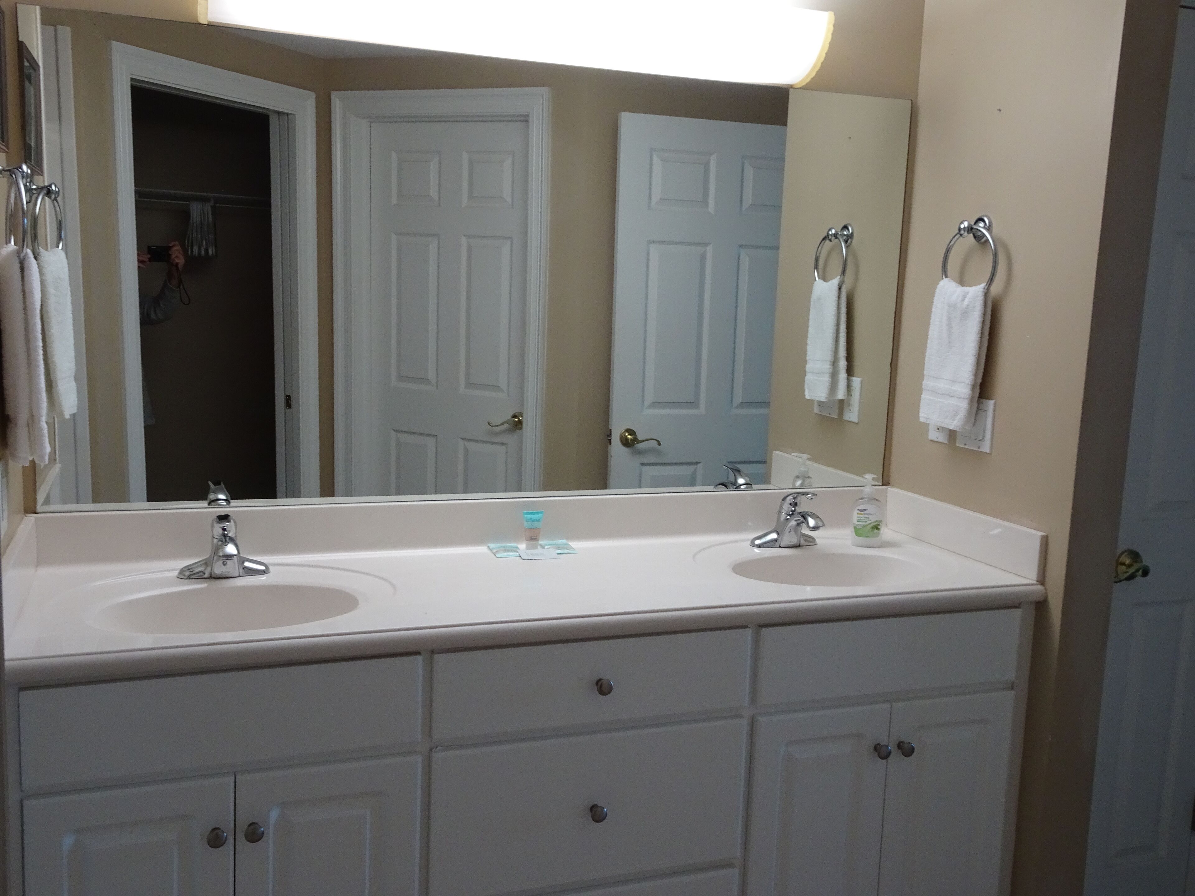 A bathroom with two sinks, a large mirror, and a towel rack.