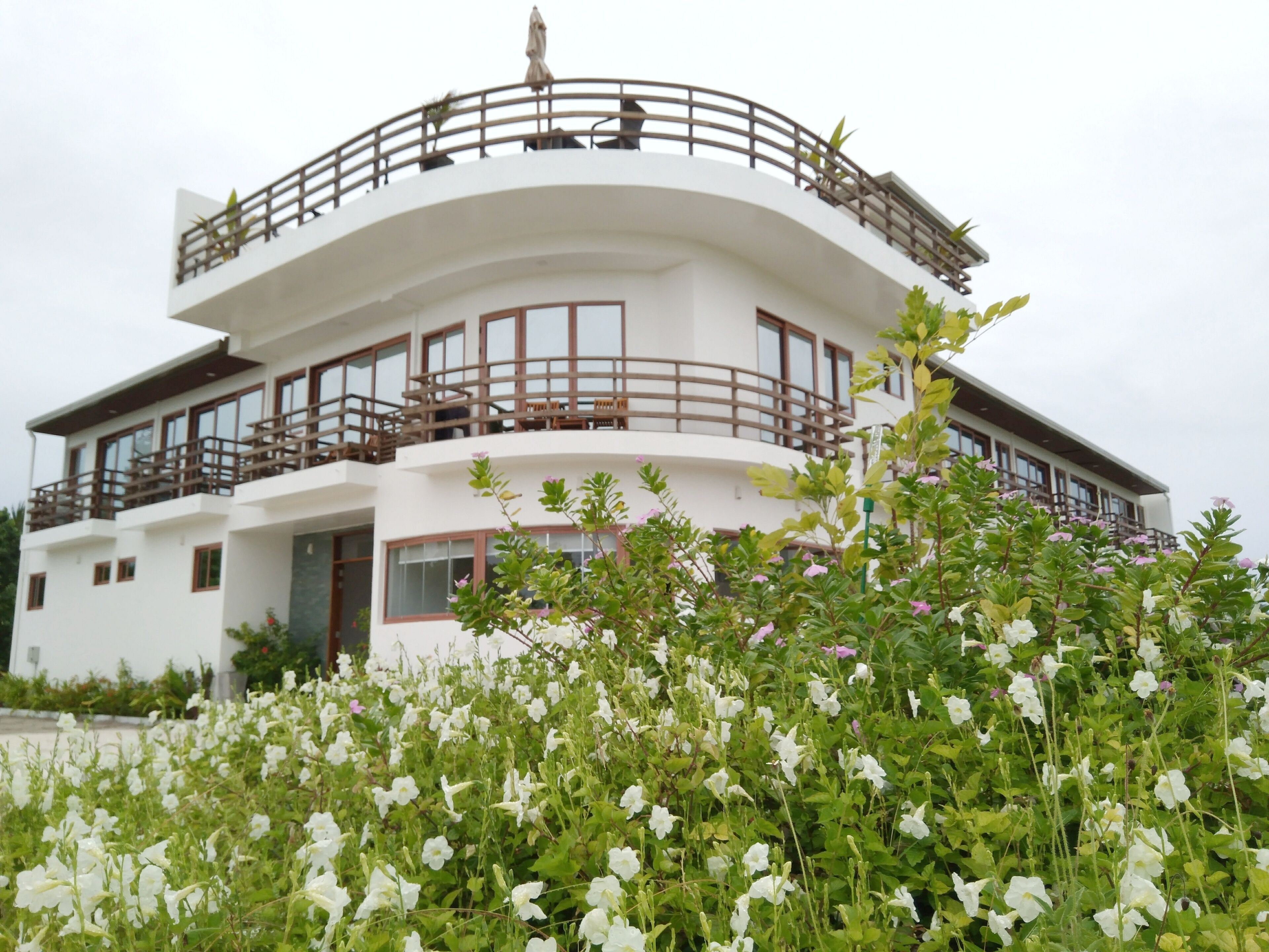A modern two-story building with balconies and a garden in the foreground.