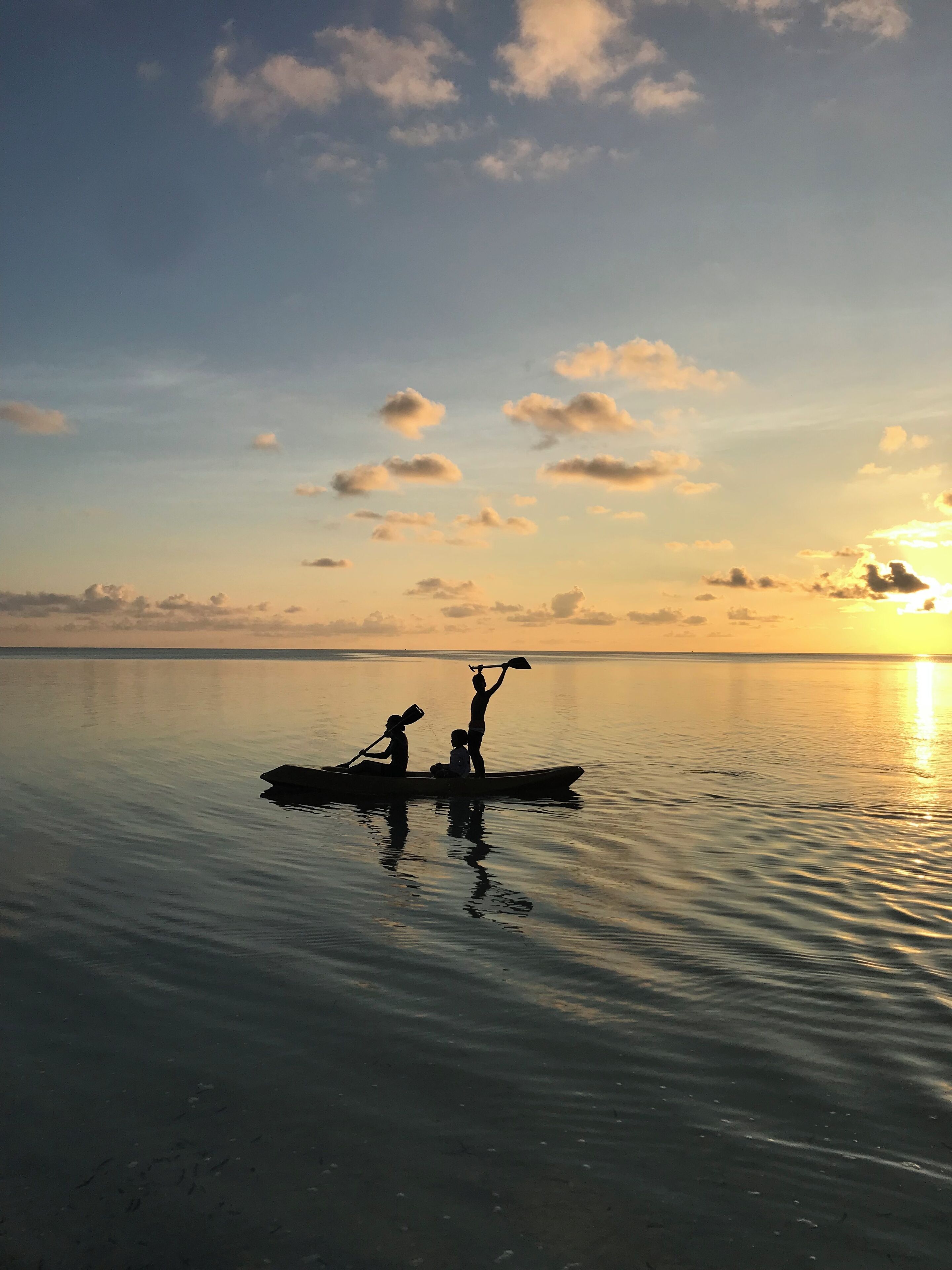 A calm body of water with a boat carrying two people paddling.