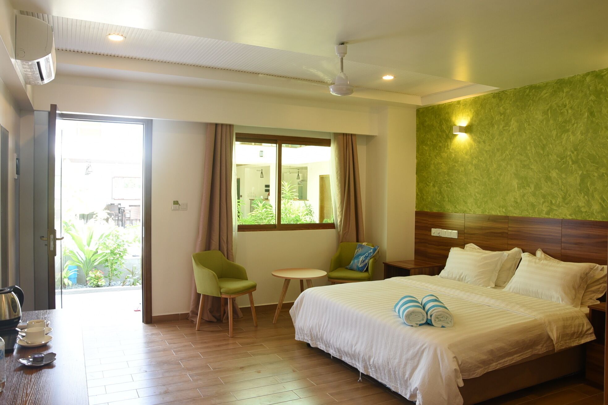 Una habitación de hotel con cama, una mesita, una silla y vistas al exterior.