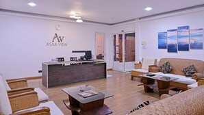 Ein Empfangsbereich mit Empfangsschalter, Sitzgelegenheiten mit Sofas und Sesseln sowie Kunstwerken an den Wänden.
