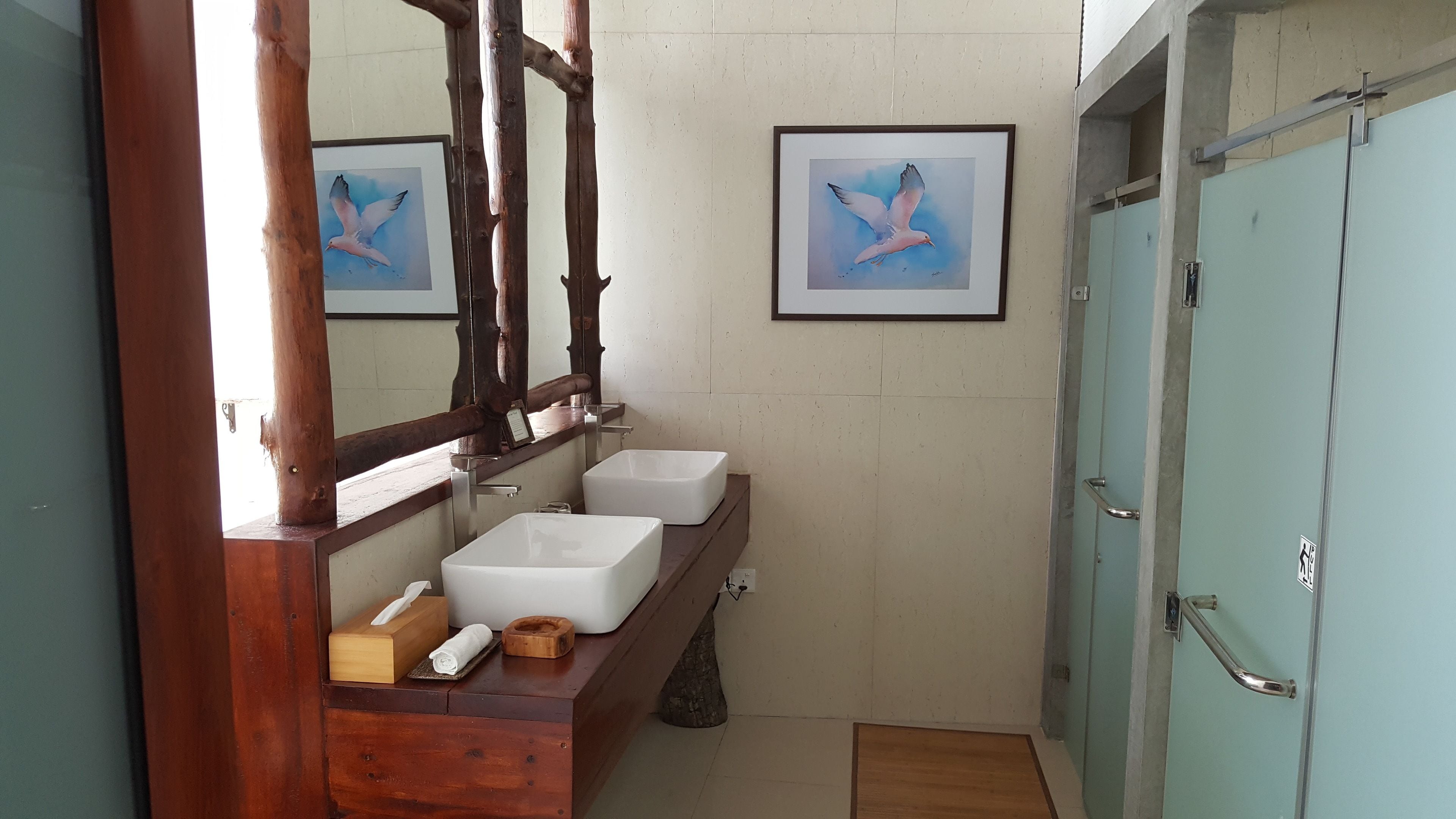 Un baño con dos lavamanos, un mueble de tocador de madera, un espejo y una puerta con barandilla.
