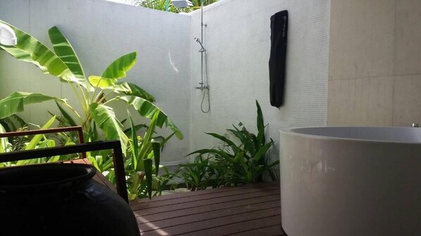 Un baño con ducha, bañera y una planta en maceta.