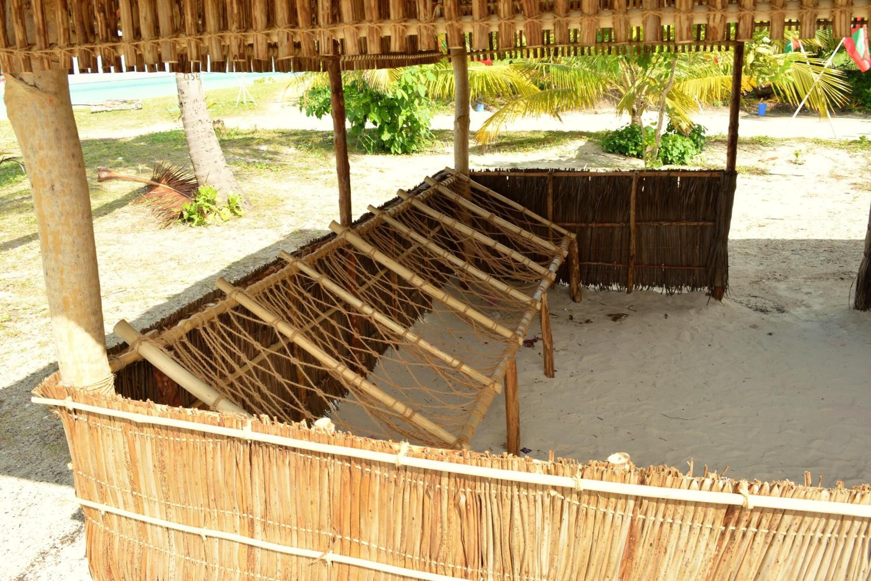 A thatched structure with a wooden bench and a woven basket.