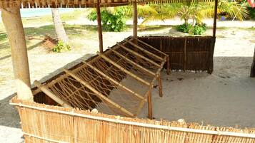 A thatched structure with a wooden bench and a woven basket.