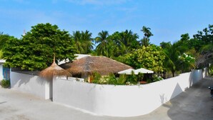 Resort com construções de palha, palmeiras e uma parede branca.