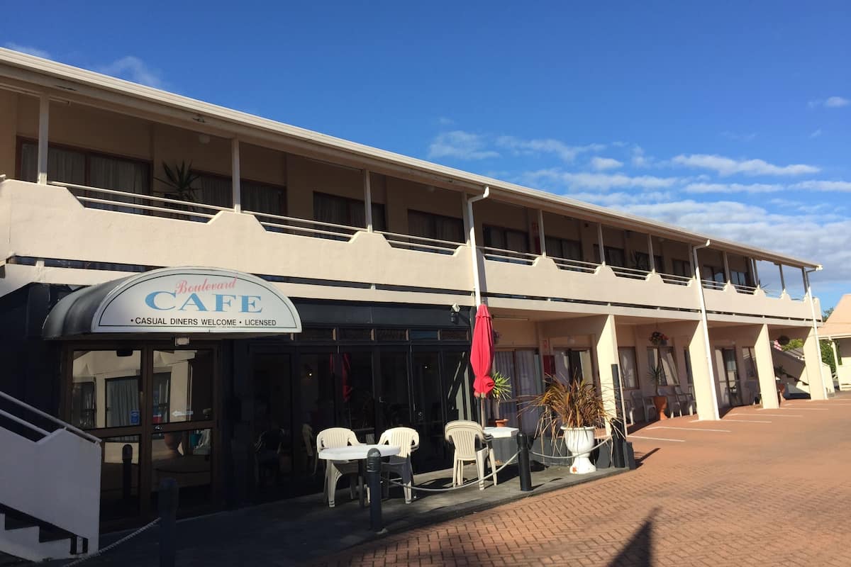 A building with a cafe sign, outdoor seating, and a covered walkway.