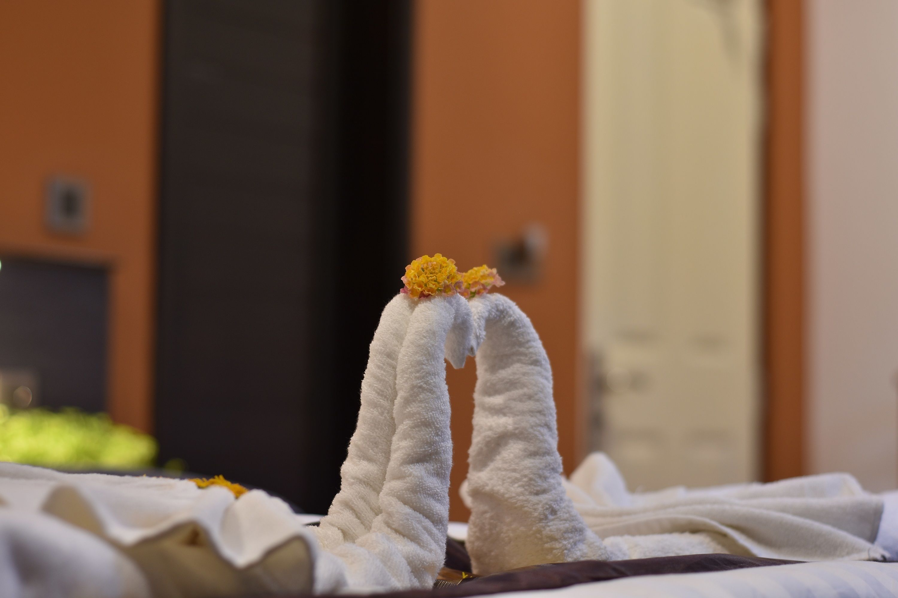 A bed with white linens and a decorative arrangement of white and yellow flowers on the pillows.