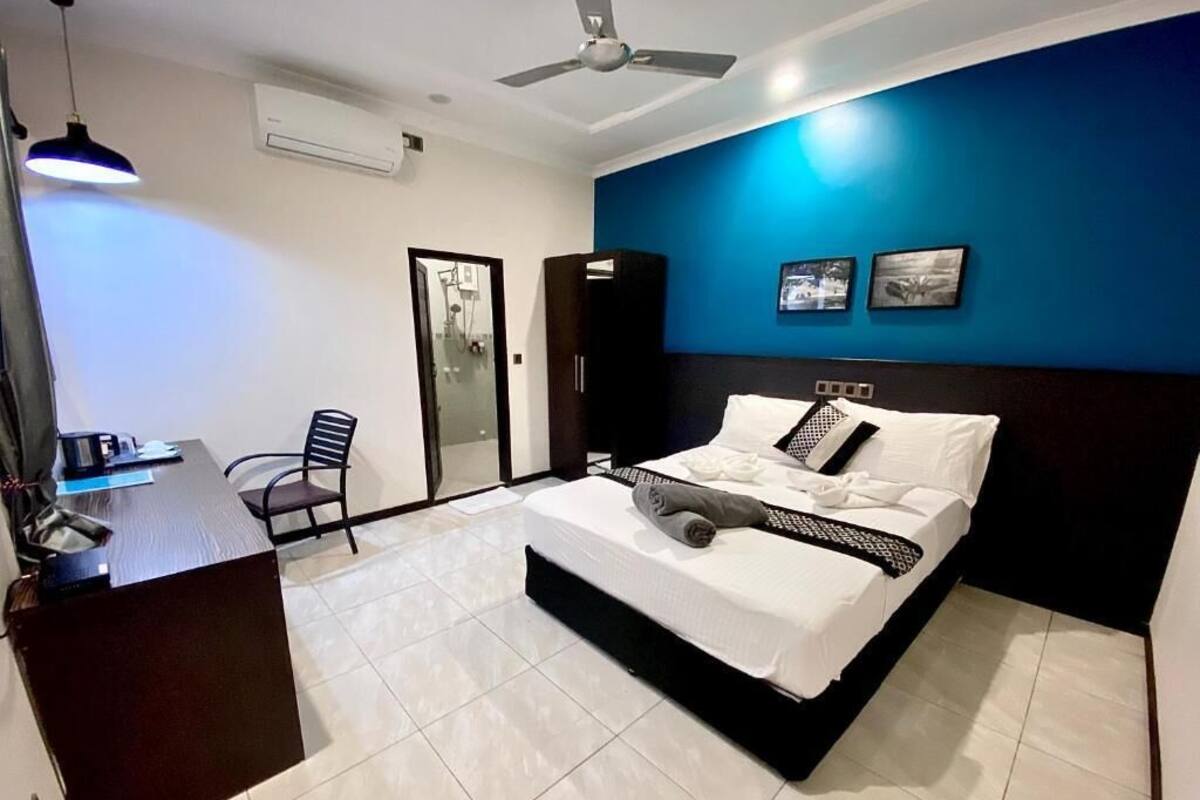 Une chambre à coucher comprenant un lit, un bureau, une chaise et un ventilateur de plafond.