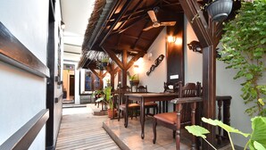 A wooden deck with a dining area, potted plants, and a ceiling fan. - Holiday Haven Ukulhas (Ukulhas)