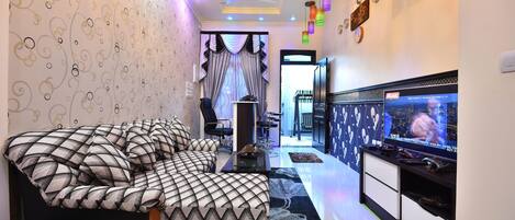 A modern bedroom with a large bed, a TV, and a ceiling fan.