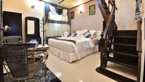 A bedroom with a bed, a chair, a table, a mirror, a ceiling fan, and a staircase. - Holiday Haven Ukulhas (Ukulhas)