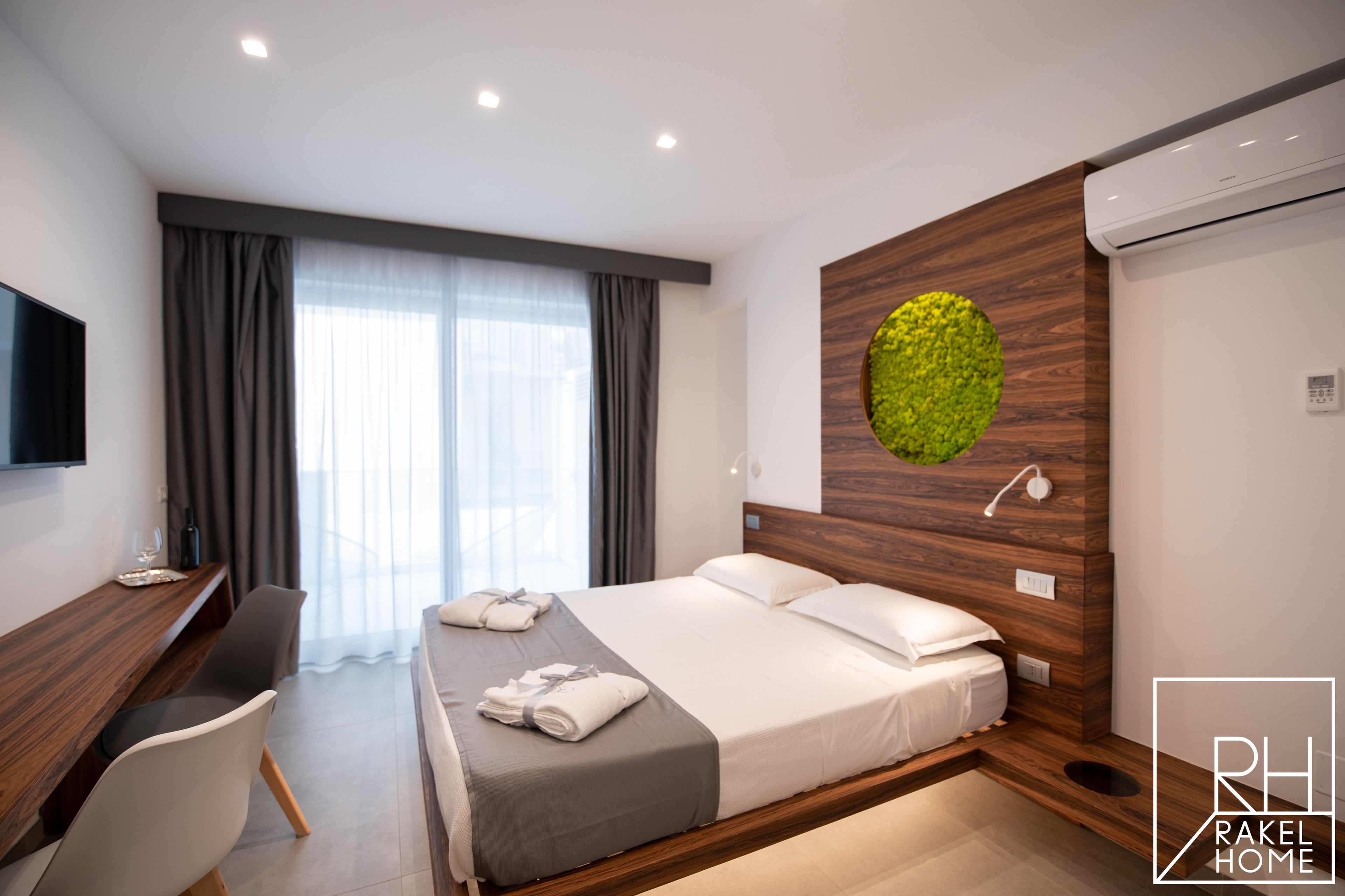 A modern hotel room with a bed, a desk, and a large window with curtains.