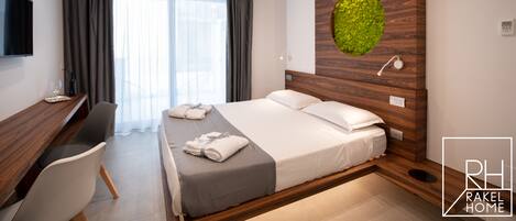 A modern hotel room with a bed, a desk, and a large window with curtains.