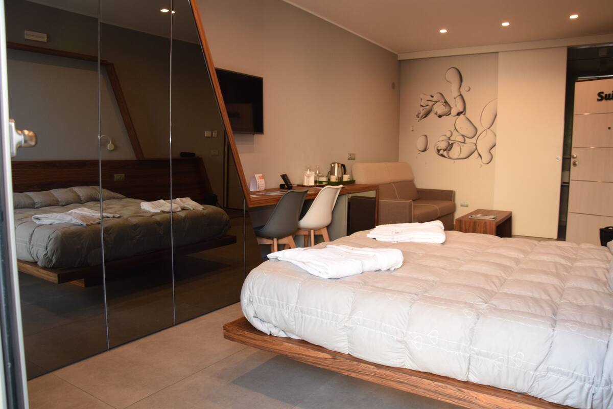 Ein modernes Hotelzimmer mit einem großen Bett, einem Schreibtisch, einem Sessel und einer Couch.