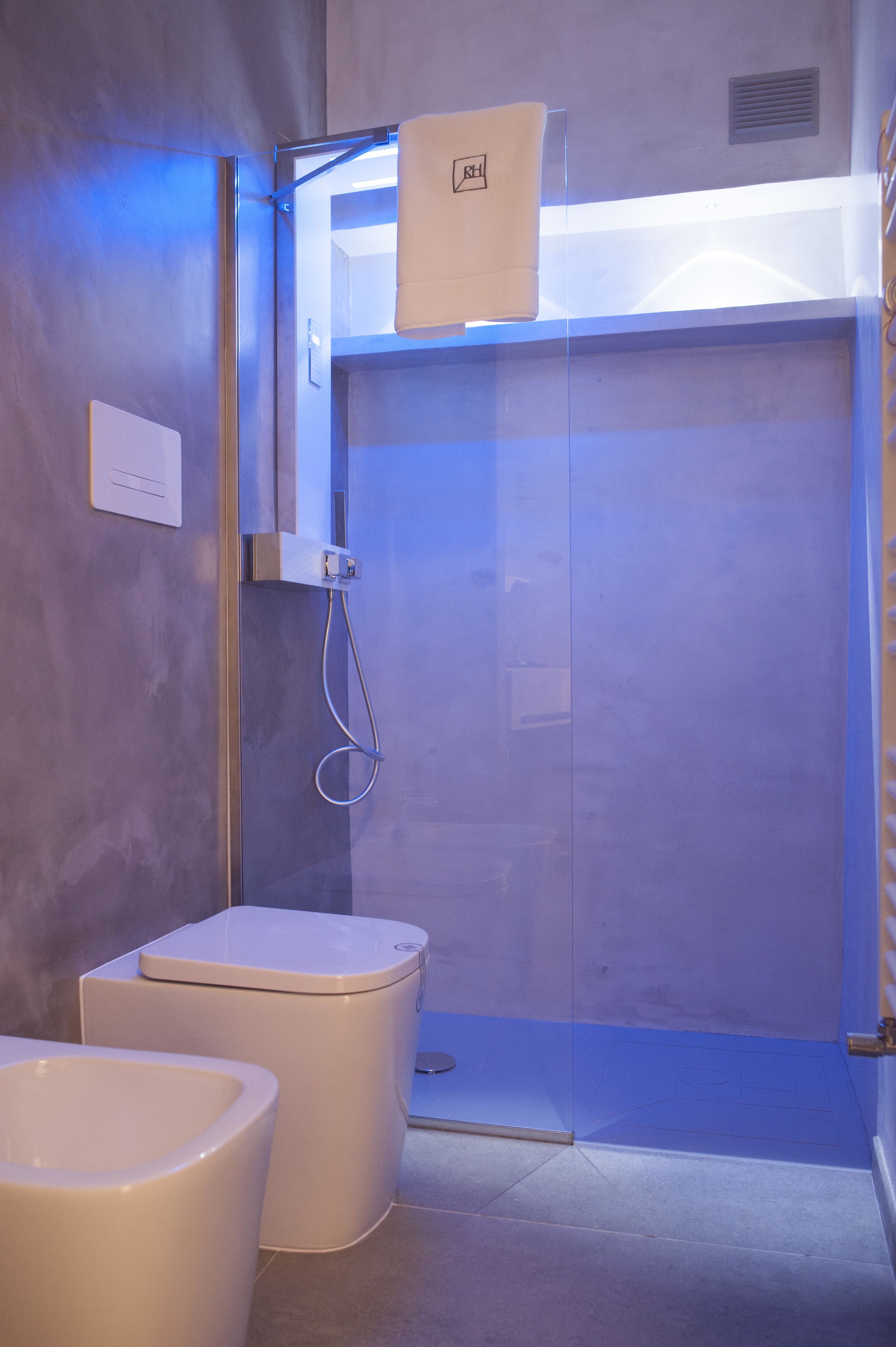 A modern bathroom with a glass-enclosed shower, a toilet, and a bidet.