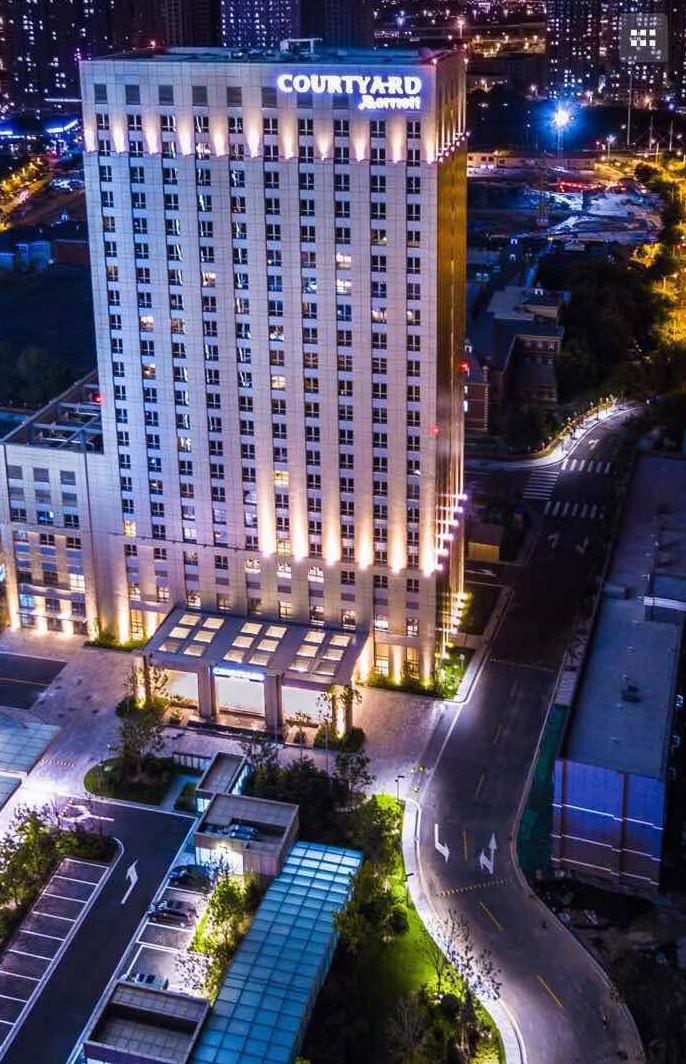 A multi-story hotel with a prominent 'COURTYARD' sign, surrounded by parking and a curved road.