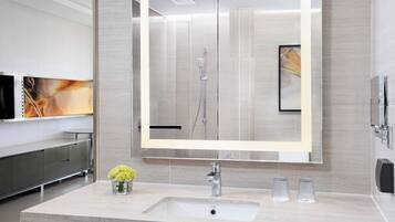 A modern bathroom with a large mirror, a sink, and a shower.