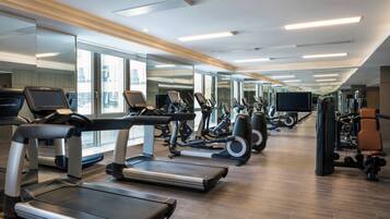 Een moderne sportschool met loopbanden, elliptische trainers en gewichttoestellen.