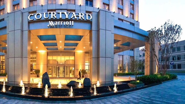 L’entrée d’un hôtel Courtyard Marriott, dotée d’un design moderne, se caractérise par une grande façade en verre et un hall d’entrée bien éclairé.