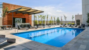 A modern outdoor pool area with lounge chairs and a covered seating area.