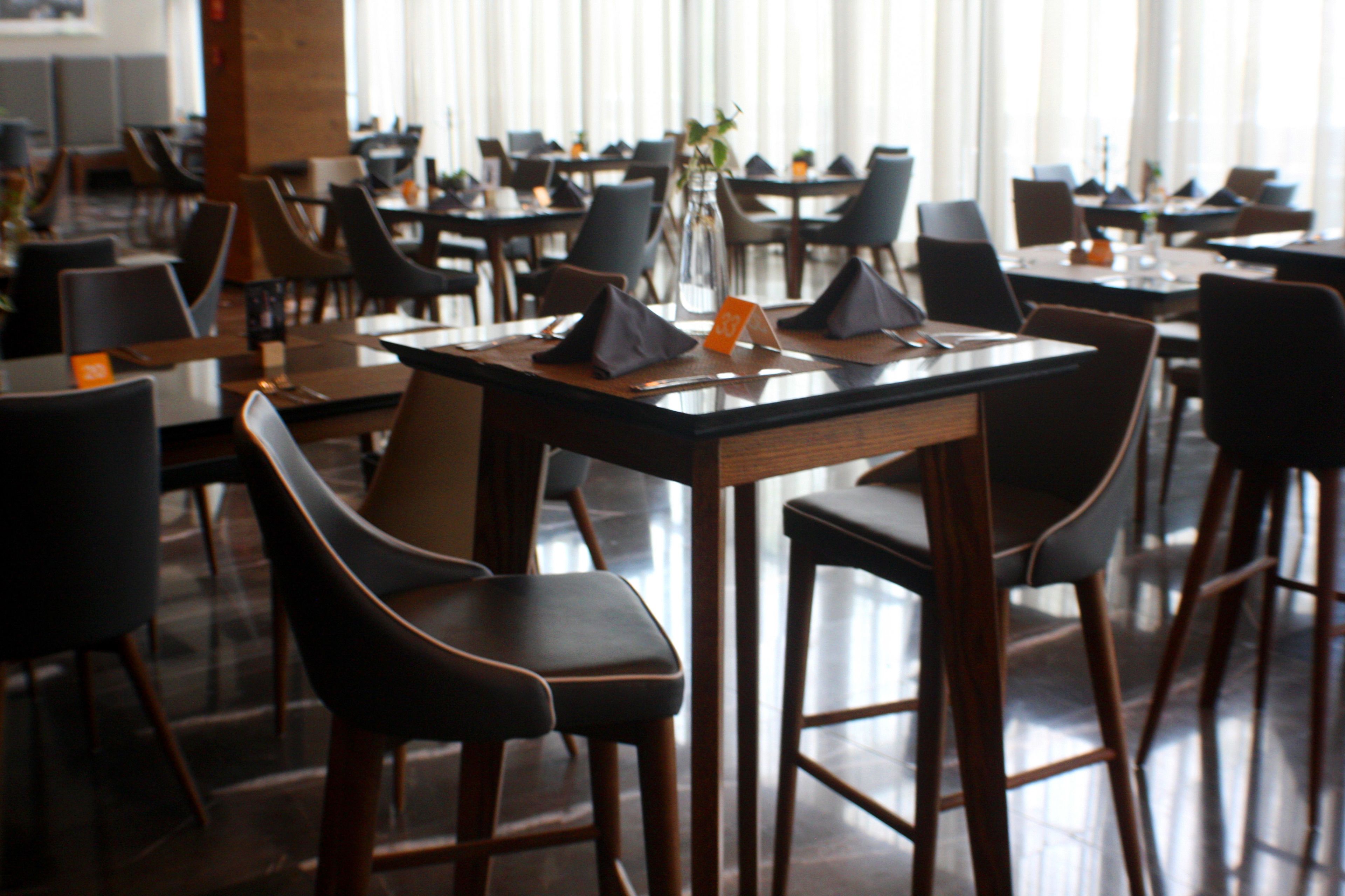 Un restaurante con varias mesas y sillas, dispuesto en un espacio amplio.