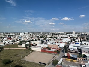 An aerial view of a cityscape with various buildings, roads, and a large open field.