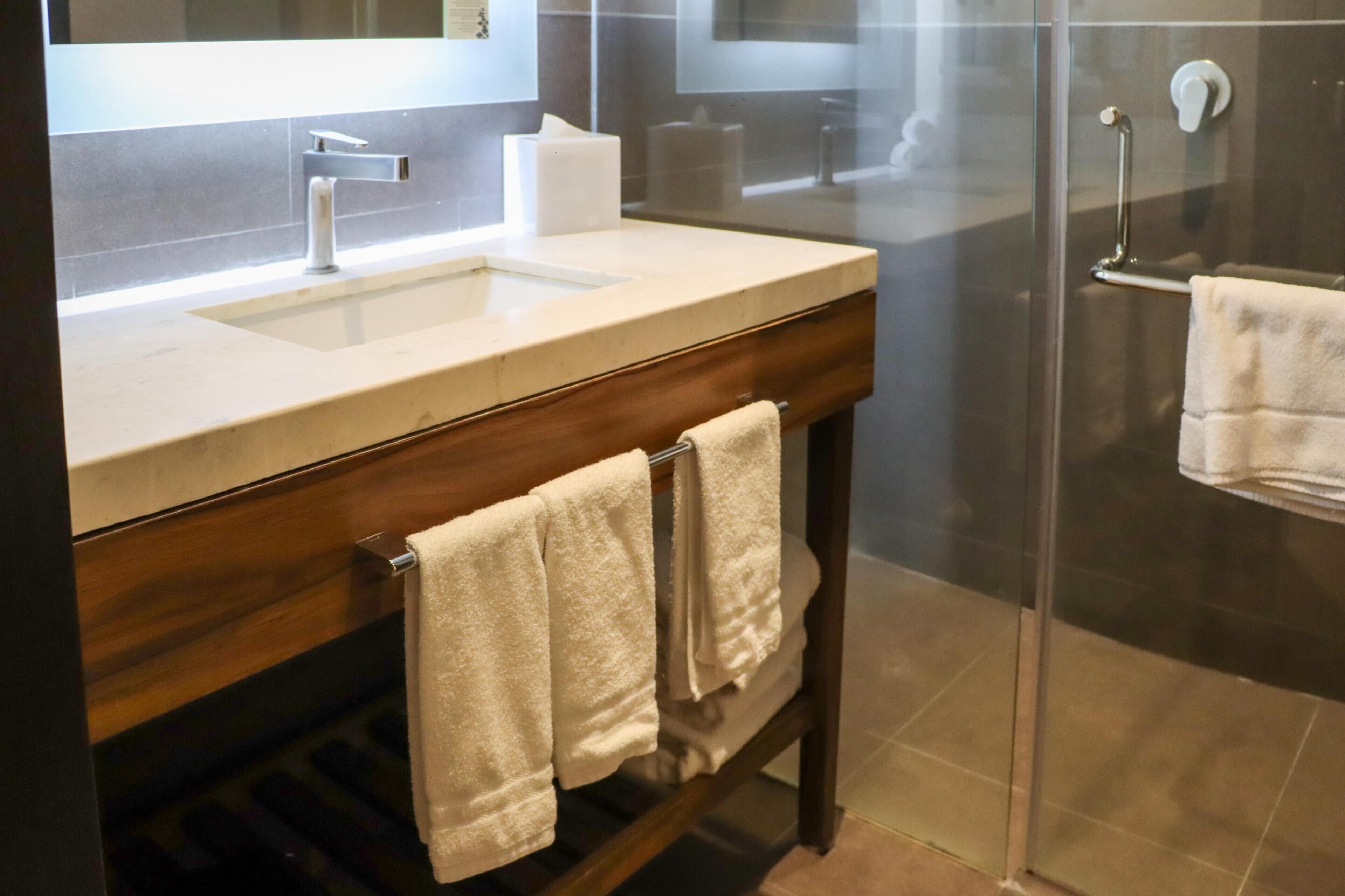A modern bathroom with a wooden vanity, a sink, and a glass shower enclosure.