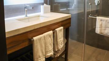 A modern bathroom with a wooden vanity, a sink, and a glass shower enclosure.