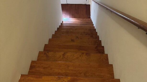 Un escalier en bois, doté d’une rampe, mène à une porte blanche située en haut.