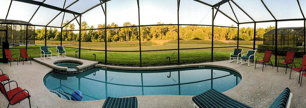 Una piscina exterior cubierta con jacuzzi, rodeada de sillas de descanso y vistas a un campo de golf.