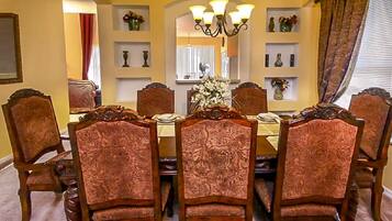 Une salle à manger avec une table ronde et six chaises, chacune ornée d’un motif complexe dans le dossier.